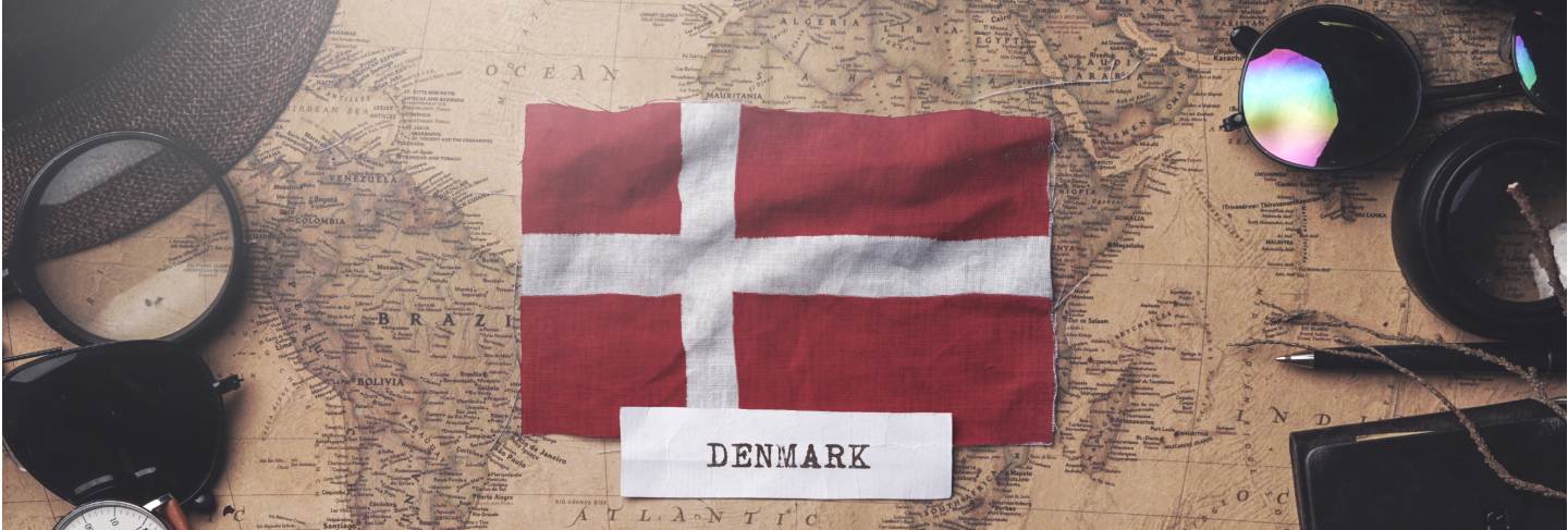 Denmark flag between traveler's accessories on old vintage map
