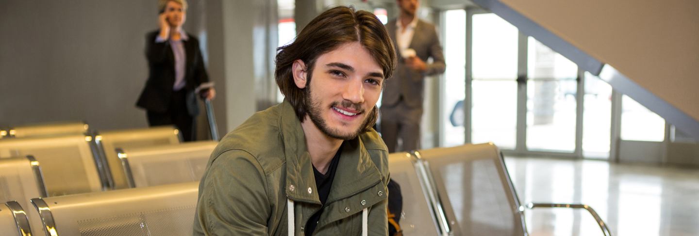 Man with passport and boarding pass sitting in waiting area
