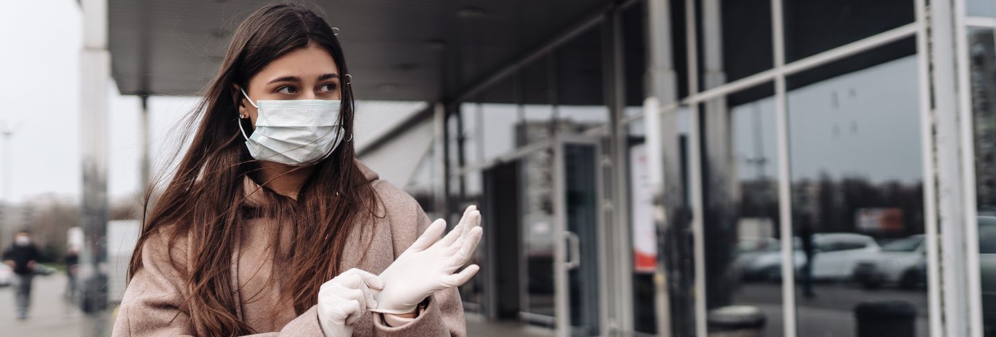 Young woman wearing protection face mask against coronavirus 2019-ncov pushing a shopping cart.
