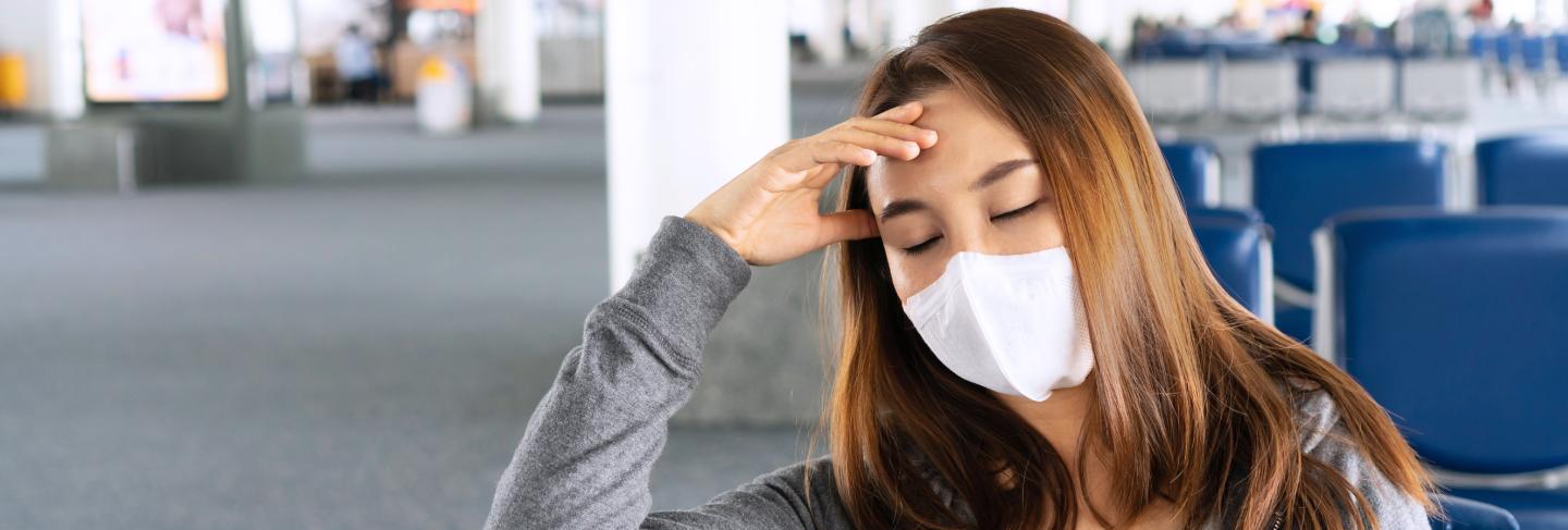 Asian woman with a surgical face mask waiting in the airport 
