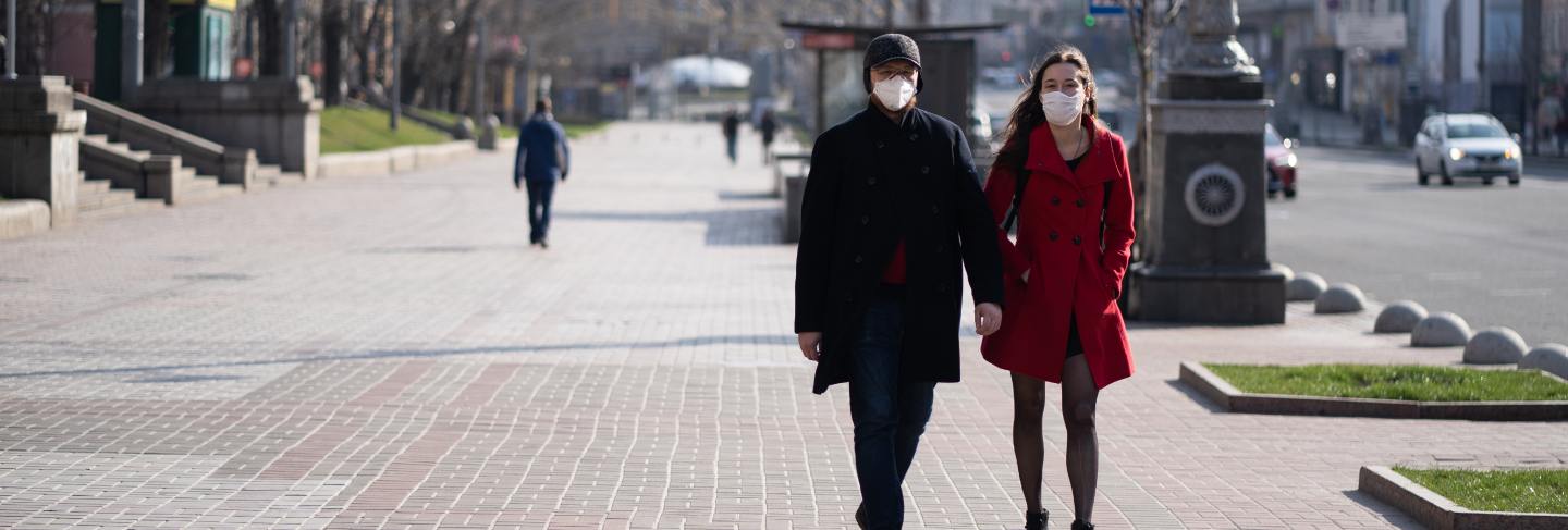 People at facial protective masks at almost empty street 
