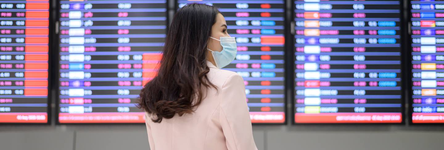 A business woman is wearing protective mask in international airport, travel under covid-19 pandemic
