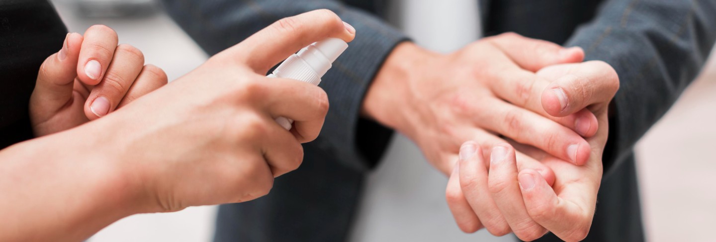 Coworkers disinfecting their hands outdoors during pandemic
