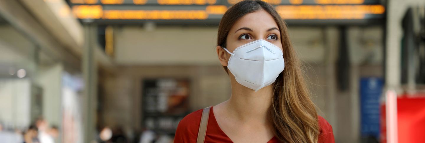 Traveler woman wearing kn95 ffp2 face mask at train station to protect from virus and smog. 
