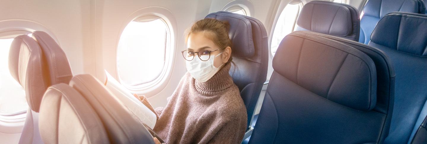 A young woman wearing face mask is traveling on airplane , new normal travel after covid-19 pandemic concept 
